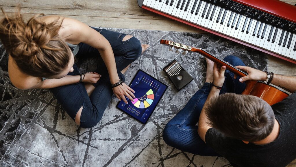 Young Couple Using Musiclabe On Ipad With Instruments Around