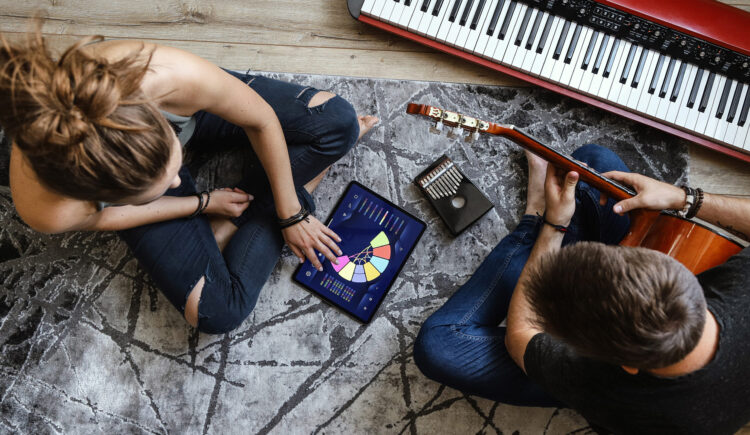 Young Couple Using Musiclabe On Ipad With Instruments Around